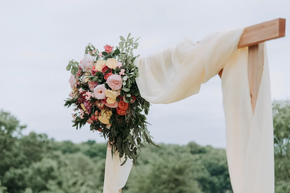 Composition florale élégante sur une table de réception de mariage avec bougies et vaisselle dorée