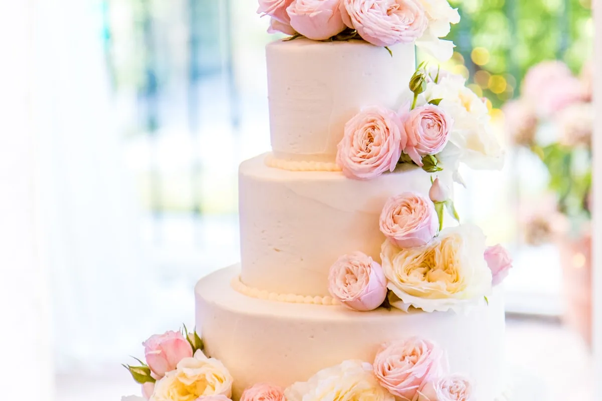 Magnifique wedding cake à trois étages décoré de fleurs fraîches et de touches dorées pour un mariage